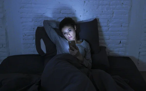 Πορτρέτο του νεαρή όμορφη γυναίκα latin χρησιμοποιώντας κινητό τηλέφωνο αργά τη νύχτα άγρυπνες ξαπλωμένη στο κρεβάτι στο σκοτάδι σε smartphone και internet dating εφαρμογή εθισμού — Φωτογραφία Αρχείου