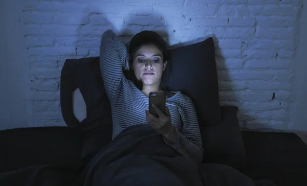 Portrait de jeune belle femme latine en utilisant le téléphone mobile tard dans la nuit sans sommeil couché dans le noir dans le smartphone et internet sortir ensemble addiction application — Photo