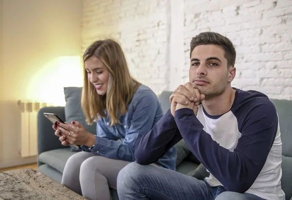 Jovem casal em casa sofá sofá com internet mulher e vício em celular ignorando seu namorado sentindo-se triste ciumento frustrado chateado — Fotografia de Stock