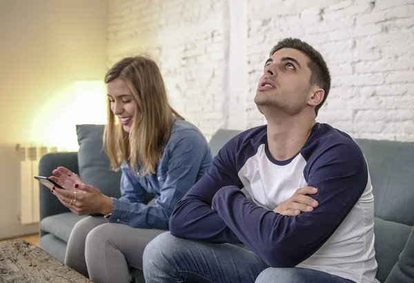 Jovem casal em casa sofá sofá com internet mulher e vício em celular ignorando seu namorado sentindo-se triste ciumento frustrado chateado — Fotografia de Stock