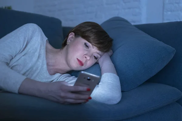 Portré, fiatal nő, 30-as ágyon heverő késő este otthon használ szociális média app mobiltelefon, fáradt és álmos — Stock Fotó