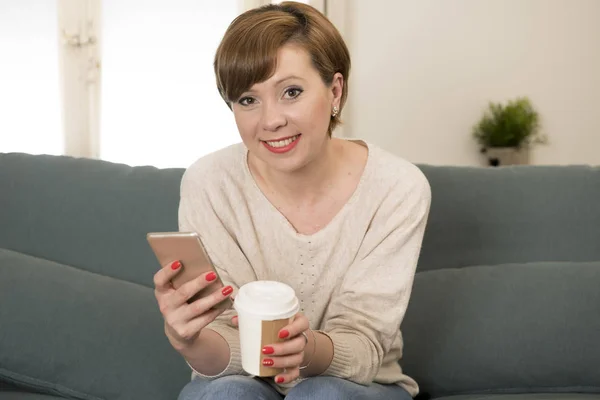 Muda menarik dan bahagia wanita rambut merah duduk di sofa rumah c — Stok Foto