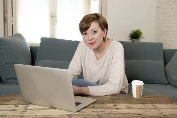 Wanita muda yang menarik dan bahagia di sofa rumah melakukan beberapa pekerjaan komputer laptop tersenyum santai dalam gaya hidup pengusaha — Stok Foto