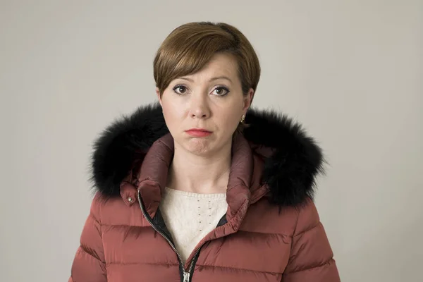 Jonge zoete en verdrietig rood haar vrouw poseren humeurig en depressief op zoek naar camera dragen van warme winter jas jas met kap geïsoleerd op grijs — Stockfoto