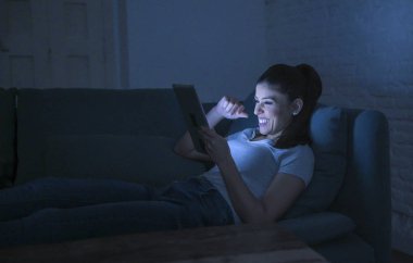 genç güzel mutlu ve rahat latin kadın 30'lu ev kanepeye geç gece internet film gülümsüyor izlerken dijital aygıt laptop tablet pad kullanarak yalan 