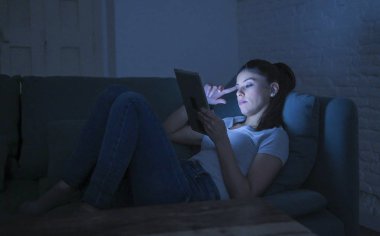 genç güzel latin kadın 30'lu bıkkın ve yorgun eve kanepeye geç gece internet film izlerken dijital aygıt laptop tablet pad kullanarak yalan 