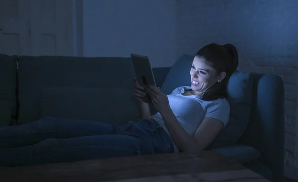 젊은 아름 다운 행복 하 고 편안한 라틴 여자 30 대 인터넷 영화 웃 고 보고 하는 디지털 장치 노트북 태블릿 패드를 사용 하 여 늦은 밤 집 소파에 누워 — 스톡 사진