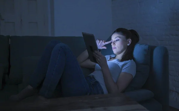 Молода красива втомлена і нудна латинка 30s лежить на домашньому дивані пізно ввечері, використовуючи цифровий пристрій планшетний набір для ноутбуків дивитися інтернет-фільм — стокове фото
