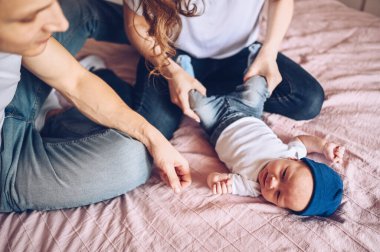 Bebeğini kucağında tutan mutlu ebeveynlerin yakın portresi. Genç, mutlu bir aile, anne ve baba yatak odasında yeni doğmuş tatlı bir çocukla oynuyorlar.