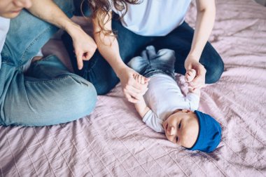 Bebeğini kucağında tutan mutlu ebeveynlerin yakın portresi. Genç, mutlu bir aile, anne ve baba yatak odasında yeni doğmuş tatlı bir çocukla oynuyorlar.