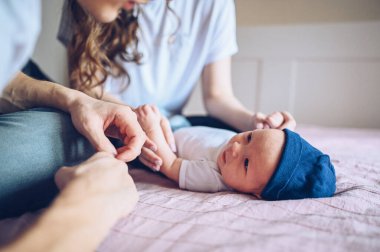 Bebeğini kucağında tutan mutlu ebeveynlerin yakın portresi. Genç, mutlu bir aile, anne ve baba yatak odasında yeni doğmuş tatlı bir çocukla oynuyorlar.