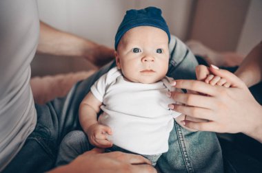 Bebeğini kucağında tutan mutlu ebeveynlerin yakın portresi. Genç, mutlu bir aile, anne ve baba yatak odasında yeni doğmuş tatlı bir çocukla oynuyorlar.