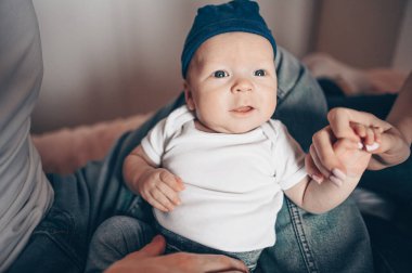 Bebeğini kucağında tutan mutlu ebeveynlerin yakın portresi. Genç, mutlu bir aile, anne ve baba yatak odasında yeni doğmuş tatlı bir çocukla oynuyorlar.