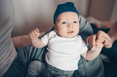 Bebeğini kucağında tutan mutlu ebeveynlerin yakın portresi. Genç, mutlu bir aile, anne ve baba yatak odasında yeni doğmuş tatlı bir çocukla oynuyorlar.