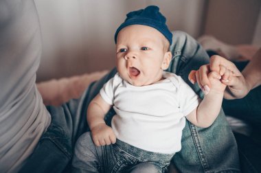 Bebeğini kucağında tutan mutlu ebeveynlerin yakın portresi. Genç, mutlu bir aile, anne ve baba yatak odasında yeni doğmuş tatlı bir çocukla oynuyorlar.