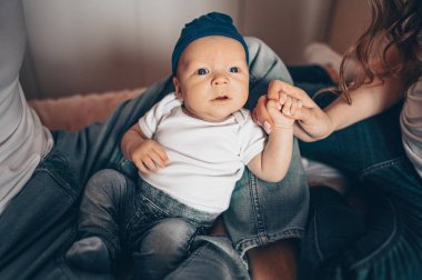 Bebeğini kucağında tutan mutlu ebeveynlerin yakın portresi. Genç, mutlu bir aile, anne ve baba yatak odasında yeni doğmuş tatlı bir çocukla oynuyorlar.