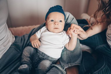Bebeğini kucağında tutan mutlu ebeveynlerin yakın portresi. Genç, mutlu bir aile, anne ve baba yatak odasında yeni doğmuş tatlı bir çocukla oynuyorlar.