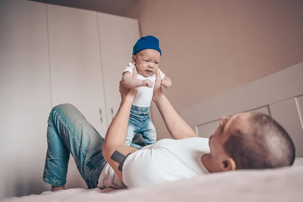청바지와 티셔츠와 모자로 아기를 아버지의 사진을 클로즈업한다 침실에서 귀여운 감정적 — 스톡 사진