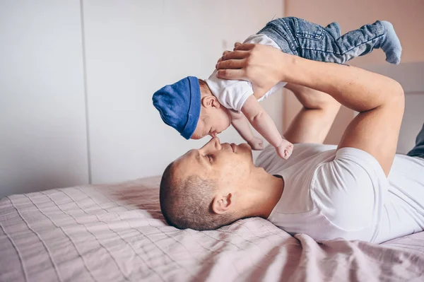 청바지와 티셔츠와 모자로 아기를 아버지의 사진을 클로즈업한다 침실에서 귀여운 감정적 — 스톡 사진