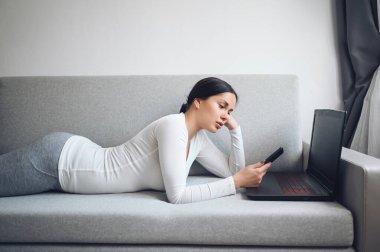 Genç Avrupalı serbest çalışan kadın Coronavirus karantinası sırasında dizüstü bilgisayar ya da telefon görüşmesi yapıyor. Covid-19 salgını Corona virüsü. Ev konseptinden çevrimiçi uzak çalışma.