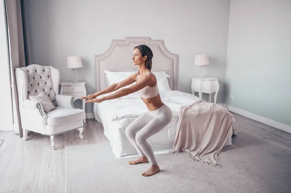 Home fitness. Young sporty fit slim woman doing morning work-out yoga exercises in bedroom at self isolation quarantine. COVID-19 concept to promote stay safe home save lives. Healthy body lifestyle
