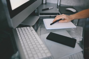 Tanımlanamayan kadın elleri boş yazılar yazarak defter ve bilgisayar hazırlıyor. Karantina sırasında akıllı telefon ve dizüstü bilgisayar kullanan serbest çalışan biri. İnternet pazarlaması, finans, iş dünyası, uzaktan çalışma kavramı
