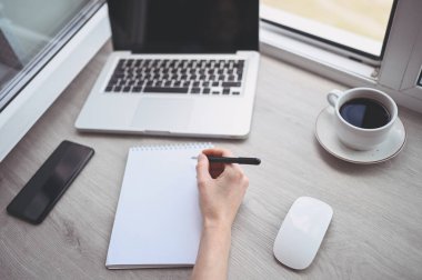 Tanımlanamayan kadın elleri boş yazılar yazarak defter ve bilgisayar hazırlıyor. Karantina sırasında akıllı telefon ve dizüstü bilgisayar kullanan serbest çalışan biri. İnternet pazarlaması, finans, iş dünyası, uzaktan çalışma kavramı