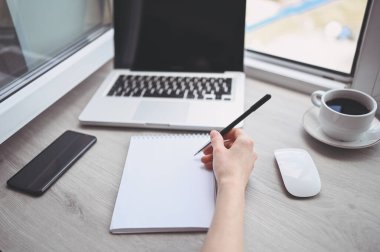 Tanımlanamayan kadın elleri boş yazılar yazarak defter ve bilgisayar hazırlıyor. Karantina sırasında akıllı telefon ve dizüstü bilgisayar kullanan serbest çalışan biri. İnternet pazarlaması, finans, iş dünyası, uzaktan çalışma kavramı