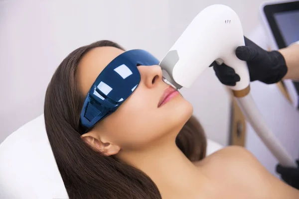 Yaşlanma karşıtı prosedürler. Deri bakımı konsepti. Kadın güzellik tedavisi görüyor, kozmetik kliniğindeki pigmentasyonu kaldırıyor. Yoğun titreşimli ışık terapisi. IPL. Yenilenme, fotoğraf yüz terapisi..