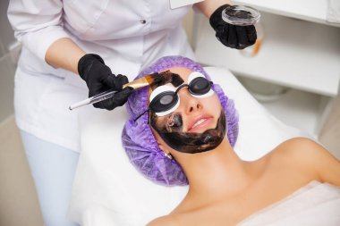 Process of carbon face laser peeling procedure in beauty salon. Laser pulses clean skin of the face. Hardware cosmetology treatment. Skin rejuvenation. Young woman with carbon nanogel on her face clipart