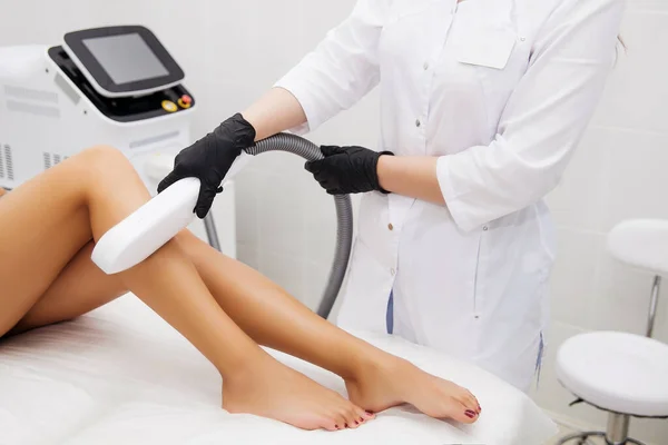 Güzellik salonunda lazer epilasyonu ve kozmetoloji. Saç çıkarma prosedürü. Lazer epilasyonu, kozmetoloji, spa ve saç temizleme konsepti. Güzel esmer kadın saçlarını bacaklarından kestiriyor.