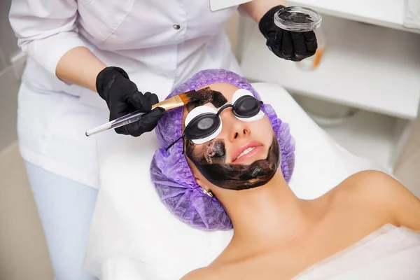 Process of carbon face laser peeling procedure in beauty salon. Laser pulses clean skin of the face. Hardware cosmetology treatment. Skin rejuvenation. Young woman with carbon nanogel on her face