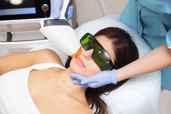 Güzellik salonunda lazer epilasyonu ve kozmetoloji. Saç çıkarma prosedürü. Lazer epilasyonu, kozmetoloji, spa ve saç temizleme konsepti. Güzel esmer kadın üst dudağındaki kılları çıkarıyor.