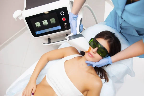 Güzellik salonunda lazer epilasyonu ve kozmetoloji. Saç çıkarma prosedürü. Lazer epilasyonu, kozmetoloji, spa ve saç temizleme konsepti. Güzel esmer kadın üst dudağındaki kılları çıkarıyor.