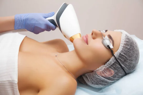 Yaşlanma karşıtı prosedürler. Deri bakımı konsepti. Kadın güzellik tedavisi görüyor, kozmetik kliniğindeki pigmentasyonu kaldırıyor. Yoğun titreşimli ışık terapisi. IPL. Yenilenme, fotoğraf yüz terapisi..