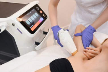 Güzellik salonunda lazer epilasyonu ve kozmetoloji. Saç çıkarma prosedürü. Lazer epilasyonu, kozmetoloji, spa ve saç temizleme konsepti. Güzel sarışın kadın koltukaltında kıl çıkarıyor.
