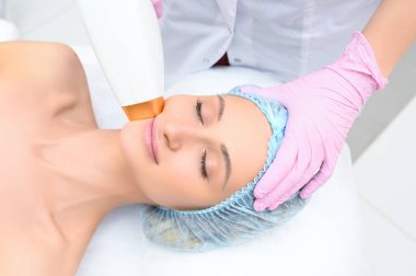 Yaşlanma karşıtı prosedürler. Deri bakımı konsepti. Kadın güzellik tedavisi görüyor, kozmetik kliniğindeki pigmentasyonu kaldırıyor. Yoğun titreşimli ışık terapisi. IPL. Yenilenme, fotoğraf yüz terapisi..