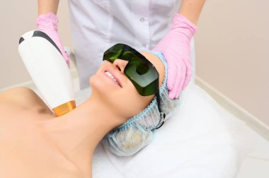 Yaşlanma karşıtı prosedürler. Deri bakımı konsepti. Kadın güzellik tedavisi görüyor, kozmetik kliniğindeki pigmentasyonu kaldırıyor. Yoğun titreşimli ışık terapisi. IPL. Yenilenme, fotoğraf yüz terapisi..