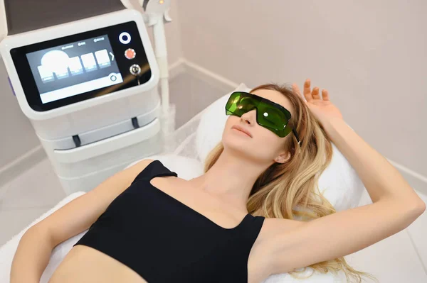 Laser epilation and cosmetology in beauty salon. Hair removal procedure. Laser epilation, cosmetology, spa, and hair removal concept. Beautiful blonde woman getting hair removing on armpits