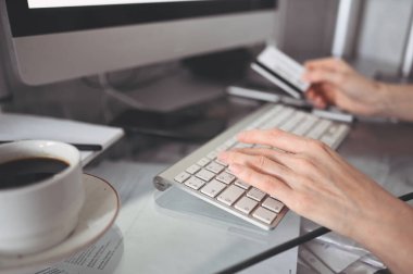 Elinde kredi kartı tutan ve dizüstü bilgisayar klavyesi kullanan tanınmamış bir kadın. İş kadını ya da girişimci çalışıyor. Çevrimiçi alışveriş, e-ticaret, internet bankacılığı, para harcama kavramı