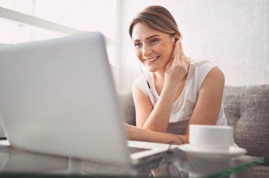 Çekici mutlu genç öğrenci evde online çalışıyor, dizüstü bilgisayar, kulaklık kullanıyor, görüntülü konuşma yapıyor, el sallıyor. Uzaktan çalışma, uzaktan eğitim. Karantina ile ilgili video konferansı veya sanal olay