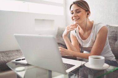 Çekici mutlu genç öğrenci evde online çalışıyor, dizüstü bilgisayar, kulaklık kullanıyor, görüntülü konuşma yapıyor, el sallıyor. Uzaktan çalışma, uzaktan eğitim. Karantina ile ilgili video konferansı veya sanal olay