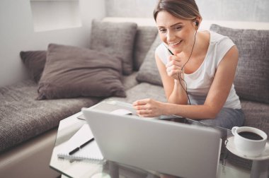 Çekici mutlu genç öğrenci evde online çalışıyor, dizüstü bilgisayar, kulaklık kullanıyor, görüntülü konuşma yapıyor, el sallıyor. Uzaktan çalışma, uzaktan eğitim. Karantina ile ilgili video konferansı veya sanal olay