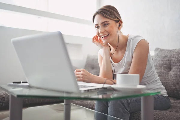 Çekici mutlu genç öğrenci evde online çalışıyor, dizüstü bilgisayar, kulaklık kullanıyor, görüntülü konuşma yapıyor, el sallıyor. Uzaktan çalışma, uzaktan eğitim. Karantina ile ilgili video konferansı veya sanal olay