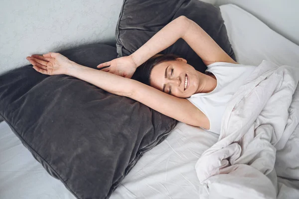 Attractive smiling young woman stretching in bed waking up alone happy concept, awake after healthy sleep in cozy comfortable bed and mattress enjoy good morning