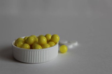 Beyaz bir zemin üzerinde beyaz bir kapakta sarı vitaminler veya tabletler