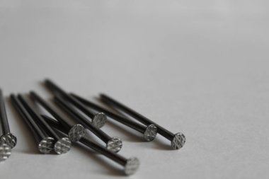 Beyaz arka planda bir yığın uzun çivi var.