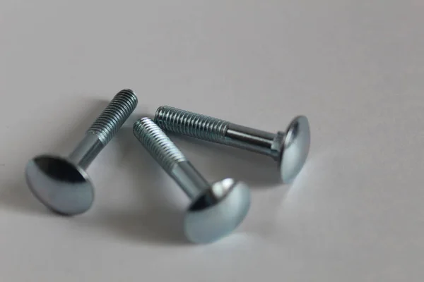 Beyaz arka planda üç büyük metal vida veya cıvata