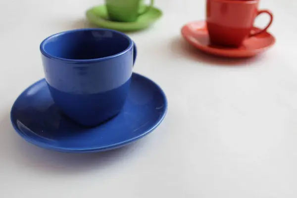blue or red Cup mug with saucer on a white background there are green and red mugs at the back with a place to insert text