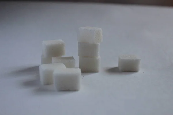 several white pieces of sugar lying in a column on top of each other on a white background